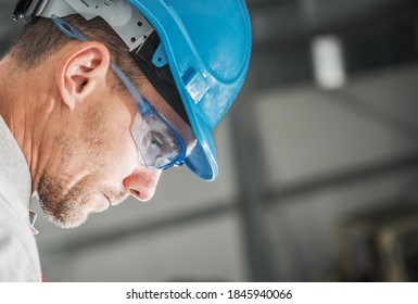 Construction Worker In His 40s In Blue Hard Hat And Eyes Safety Glasses Profile Portrait. Working Day.