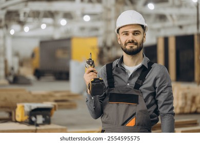 Construction worker holding cordless drill in modular building factory, showcasing expertise in prefabricated construction
