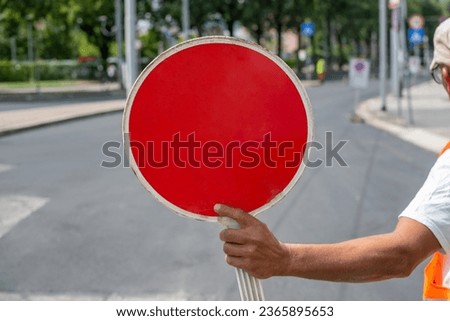 Construction worker holding a Red Stop Sign and directing traffic on the street
