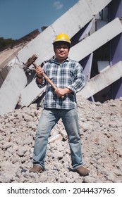 Construction Worker Holding A Sledge Hammer Standing On Demolish Building And Looking At The Camera. Earthquake. Industry.