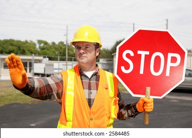 A Construction Worker Holding A Stop Sign And Directing Traffic.