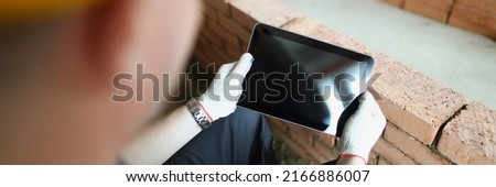 Construction worker holding tablet with black turned off screen