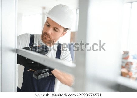 Construction worker installing metal profile for interior partition wall, while building a new house or renovation process, viewed from his back
