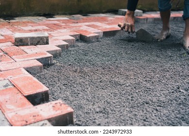 construction worker installing pavestone using coarse sand as bedding 