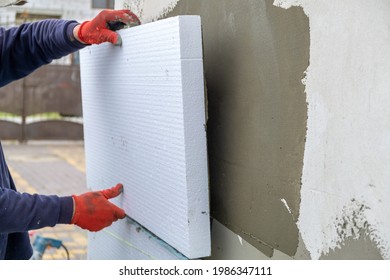 Bauarbeiter, die Styropor-Isolierplatten auf der Fassadenwand des Hauses für den thermischen Schutz installieren.