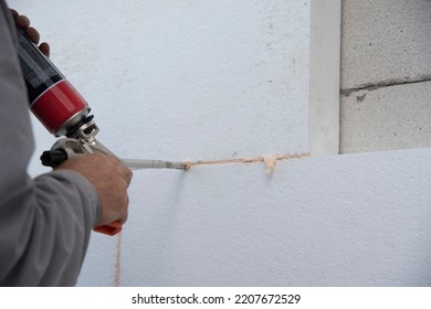 Construction Worker Installing Styrofoam Insulation Sheets And Filling Space Between With Expanding Foam On House Facade Wall For Thermal Protection. Thermal Insulation.