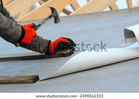 Construction Worker Installing Underlayment on Roof