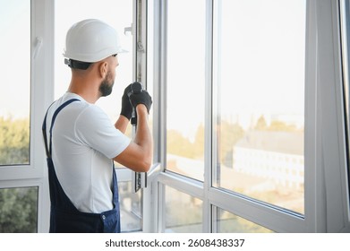 Construction worker installing window in house. Handyman fixing the window with screwdriver.