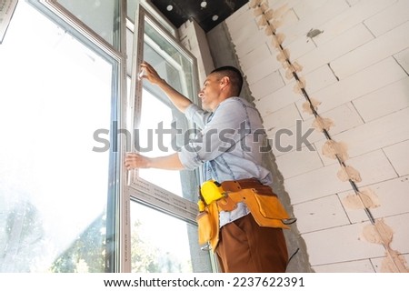 Construction worker installing window in house