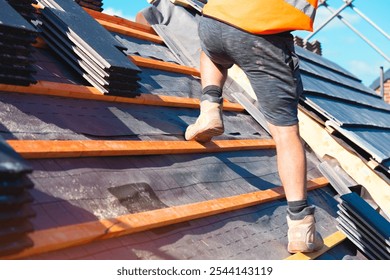 A construction worker installs solar panels on a residential rooftop under clear blue skies in the morning - Powered by Shutterstock