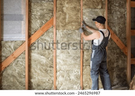 a construction worker insulates the wall of a frame house with insulation. copy space.