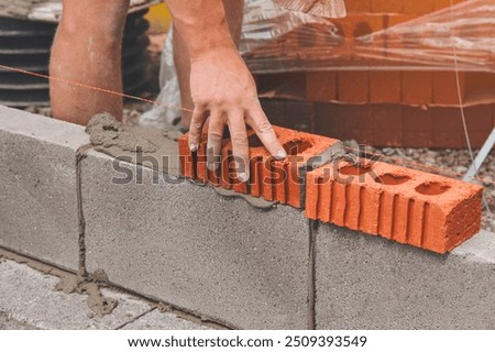 Construction Worker Laying Bricks During Building Project in the Afternoon Sun
