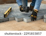 Construction worker laying cement pavement on a walkway with gloves and rubber hammer. House improvement.