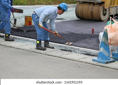 Construction worker leveling asphalt.