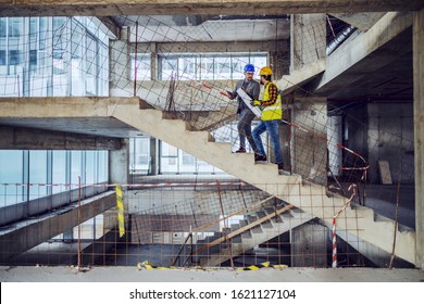 Construction worker and main architect climbing the stairs and talking about progress in construction of new building.