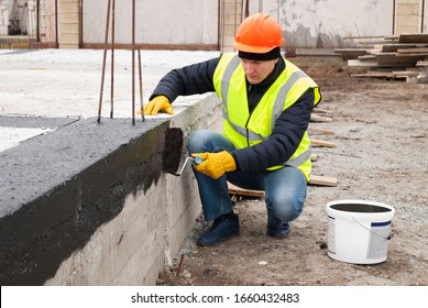 Construction Worker Makes Bituminous Waterproofing Of The Foundation At The Construction Site