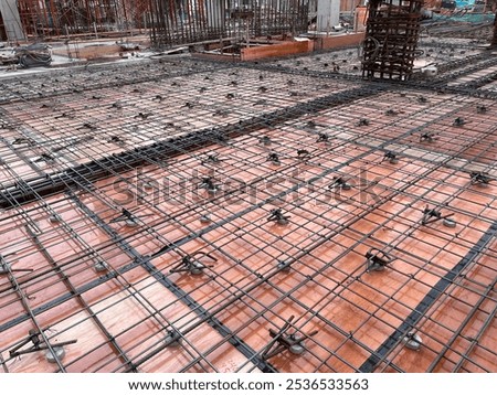 Construction worker making and assembling iron reinforcement for floor slabs at construction site.