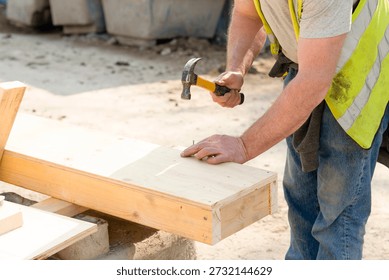 Construction worker making shutter  formwork from timber and plywood for concrete pour using hammer and nails on construction site