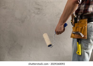 Construction worker man holding paint roller tool near wall. Male hand and construction tools for house room renovation. Home renovation concept - Shutterstock ID 2029260092
