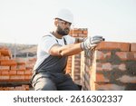 Construction worker man in work clothes and a construction helmet. Portrait of positive male builder in hardhat working at construction site.