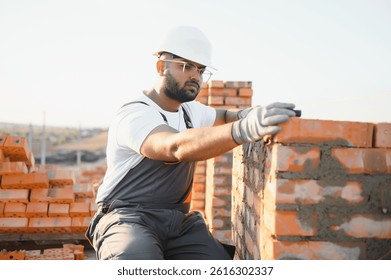 Construction worker man in work clothes and a construction helmet. Portrait of positive male builder in hardhat working at construction site.