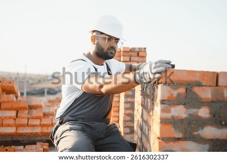 Construction worker man in work clothes and a construction helmet. Portrait of positive male builder in hardhat working at construction site.