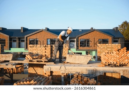 Construction worker man in work clothes and a construction helmet. Portrait of positive male builder in hardhat working at construction site.