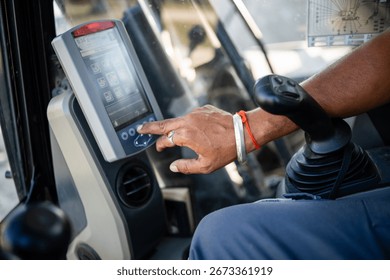 Construction worker managing settings on a digital control panel inside of an excavator, showcasing technological advancements in modern construction equipment
