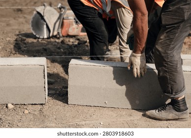 Construction worker manually adjusting concrete curb stone during sidewalk pavement installation. Perfect for road repair contractors, urban paving services, and masonry websites.