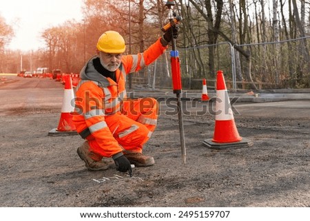 Construction Worker Marking Road Surface With Chalk in Daytime