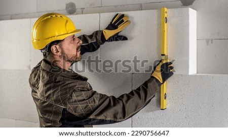 a construction worker measures the verticality of the internal insulation system with a spirit level.