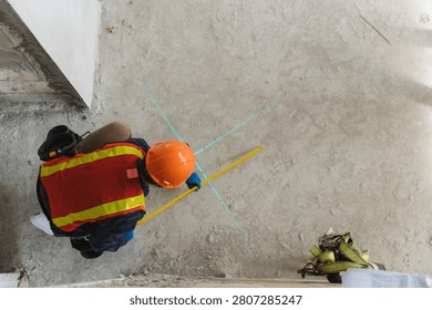 Construction worker measuring and marking floor with laser level for accurate measurements in building project