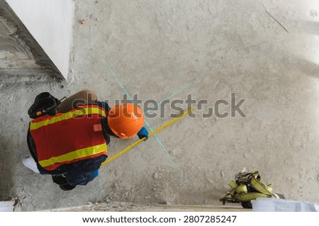 Construction worker measuring and marking floor with laser level for accurate measurements in building project