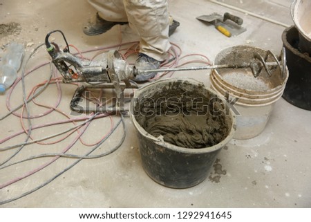 The construction worker mixes tile adhesive together with the water in the correct proportions.
