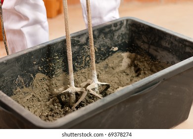 Construction Worker Mixing Concrete Or Grout With A Hand Mixer