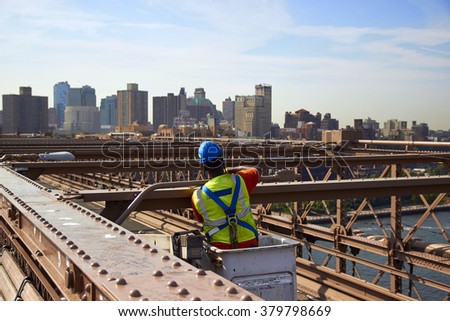 Construction worker on Brooklyn Bridge at sunny day.