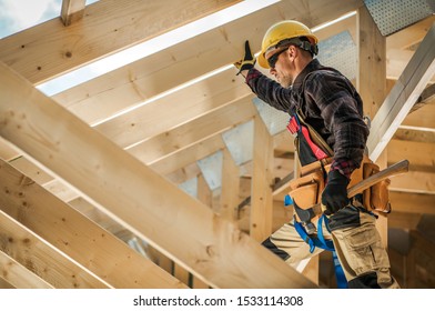 Construction Worker on Duty. Caucasian Contractor and the Wooden House Frame. Industrial Theme.