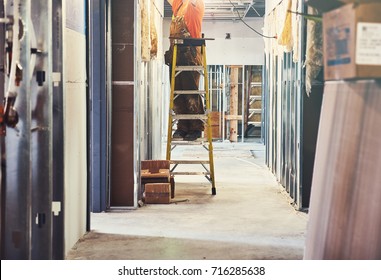 Construction Worker On A Ladder Fixing Lighting