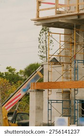 Construction Worker on Scaffolding at Concrete Building Site Wearing Safety Gear on Upper Floor in St. Pete Beach FL Wooden scaffolding at a concrete building site, surrounded by tools, safety rails and urban street lighting during daytime.
