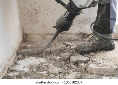Construction worker on construction site with demolition hammer - chiseling close-up