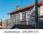 Construction worker on top of properly secured scaffolding preparing the wall for new plaster