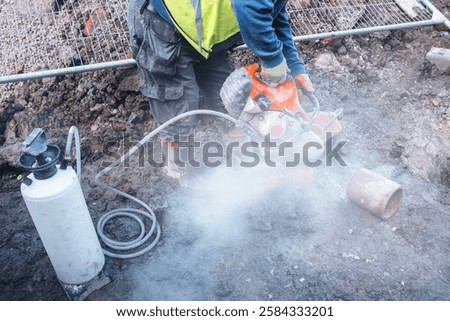 Construction worker operates a power petrol cutter at a construction site during the day