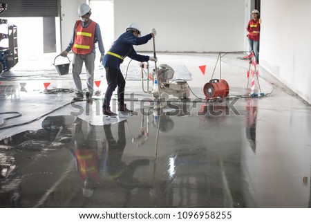 Construction worker painting epoxy flooring or floor hardener