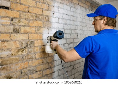 Construction Worker Painting Old Brick Wall In White Color With Paint Sprayer