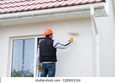 Construction Worker Is Painting A Wall With A Roller