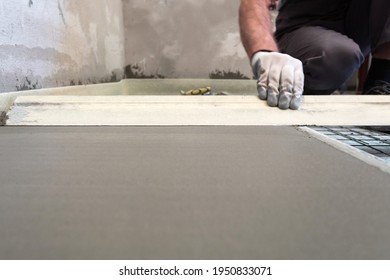 Construction worker performs floor screed indoors. Leveling the floor. - Shutterstock ID 1950833071