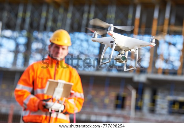 Construction worker piloting drone\
at building site. video surveillance or industrial\
inspection
