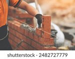 Construction Worker Placing Brick in Brick Wall During Daytime