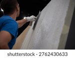 Construction worker plastering an interior wall with a trowel during renovation project