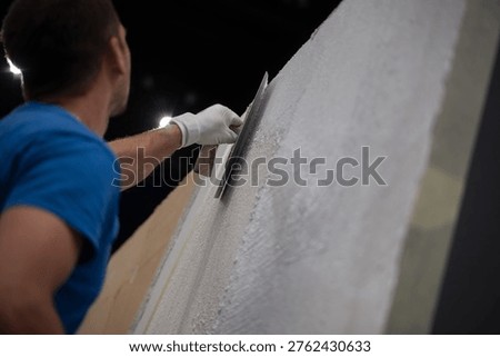 Construction worker plastering an interior wall with a trowel during renovation project